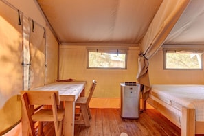 A tent with a wooden table, a chair, a small air conditioning unit, and a bed. - Amazing Tented Cabin with Awesome Sights in Johnson City, Texas (Johnson City)