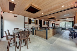 A spacious kitchen with wooden cabinetry, a central island, and a dining area with chairs. - Amazing Tented Cabin with Awesome Sights in Johnson City, Texas (Johnson City)