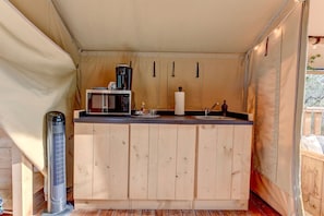 Pieni, käytännöllinen keittiö, jossa on mikroaaltouuni, vedenkeitin ja pesuallas.