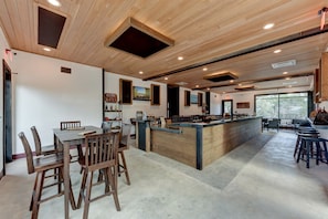 A spacious kitchen with wooden cabinetry, a central island, and a dining area with chairs. - Amazing Tented Cabin with Awesome Sights in Johnson City, Texas (Johnson City)