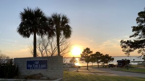 A sign for 'On the Lake RV Resort' with a sunset in the background.