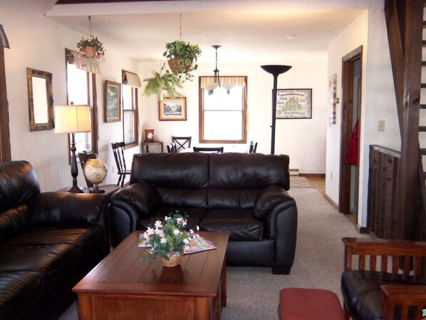 A living room with a leather sofa, wooden coffee table, and a globe. - Cottage Rental on Chappaquiddick Island with Transferable Ferry Ticket Availability Massachusetts (Edgartown)