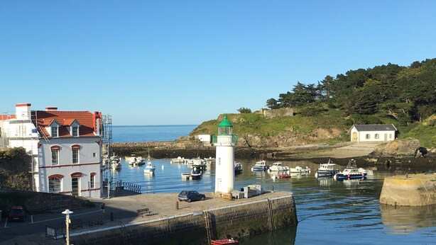 Un port avec des bateaux, un phare et des bâtiments le long de la rive.