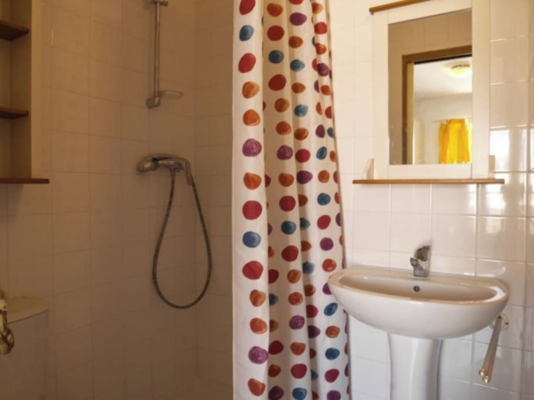 Un baño con ducha, lavamanos y espejo.