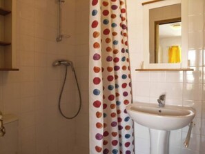 Un baño con ducha, lavamanos y espejo.