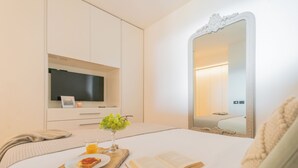 A neatly made bed with a book, a glass of orange juice, and a plate with toast. - Skyline Lake Apartment (Como)