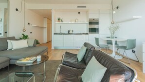 A modern living room with a sofa, coffee table, and a dining area with chairs and a table. - Skyline Lake Apartment (Como)