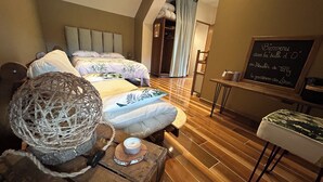 Un dormitorio con dos camas, suelo de madera, una mesita con una vela y una pizarra con un mensaje de bienvenida.