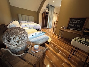 Ein Schlafzimmer mit zwei Betten, Holzboden, einem kleinen Tisch mit Kerze und einer Tafel mit einer Willkommensbotschaft.
