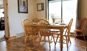 A dining area with a wooden table and chairs, a mirror on the wall, and a window with a view. - 4-Bedroom Apartment at Blue Mountain · Walk to Village · Private Beach Access (Collingwood)