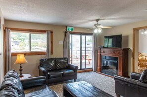 A living room with a sofa, a coffee table, a fireplace, and a television. - 4-Bedroom Apartment at Blue Mountain · Walk to Village · Private Beach Access (Collingwood)