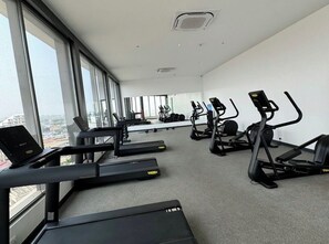 Ein Fitnessraum mit Laufbändern, Ergometer und einem Laptop auf einem Schreibtisch.