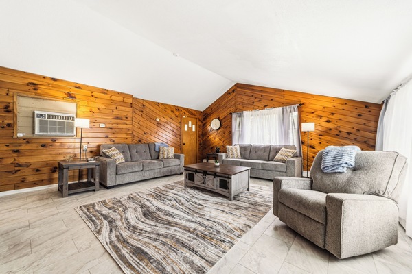 Gather with family and friends in the spacious living area featuring comfortable seating and soaring wood-accented ceilings.