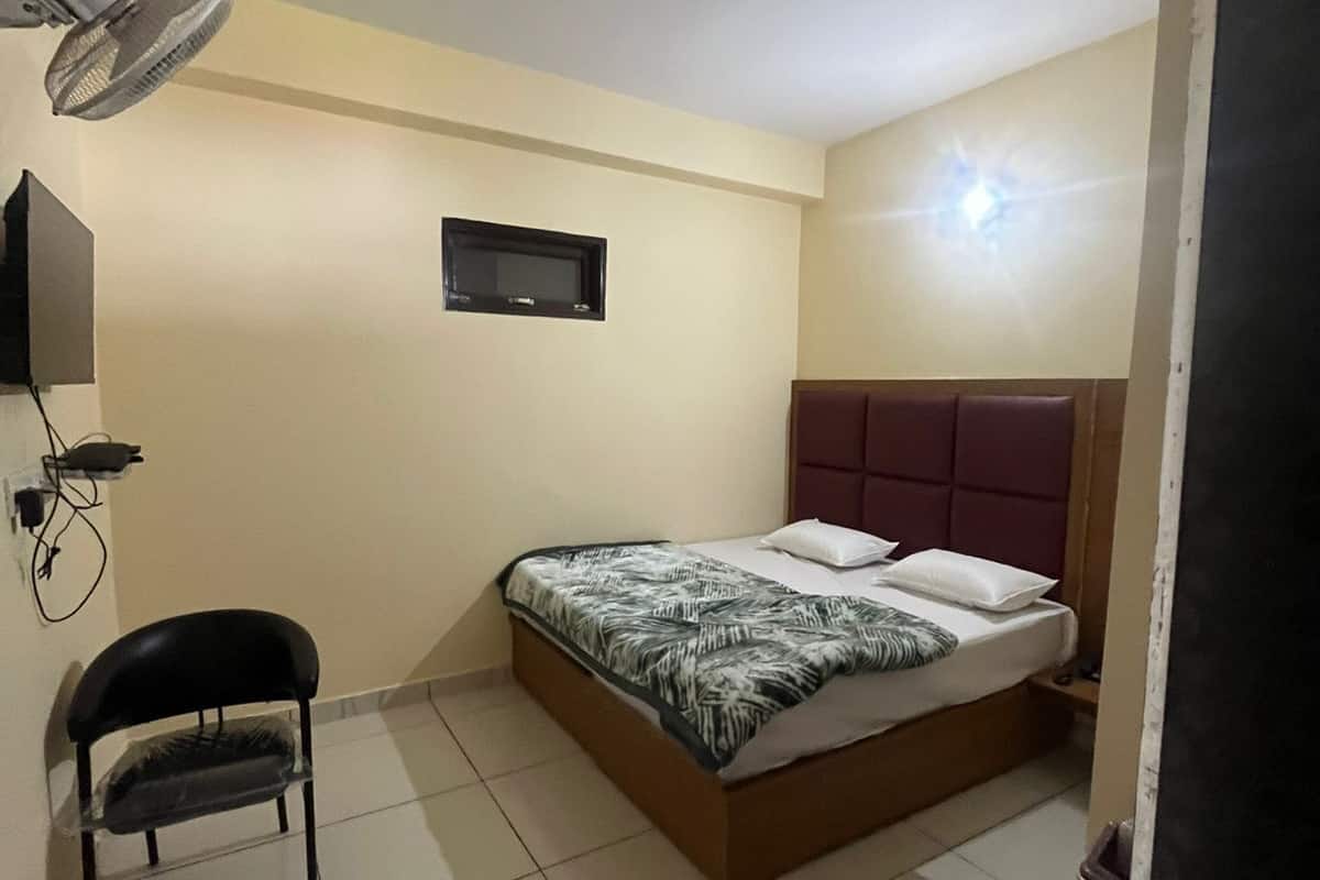 A bedroom with a bed, a chair, a TV, and a ceiling fan.