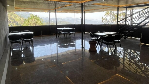 A modern interior with a panoramic view, featuring a dining area with tables and chairs, a staircase, and a polished floor. - The Classic Residency Hotel & Banquet  (Shimla)
