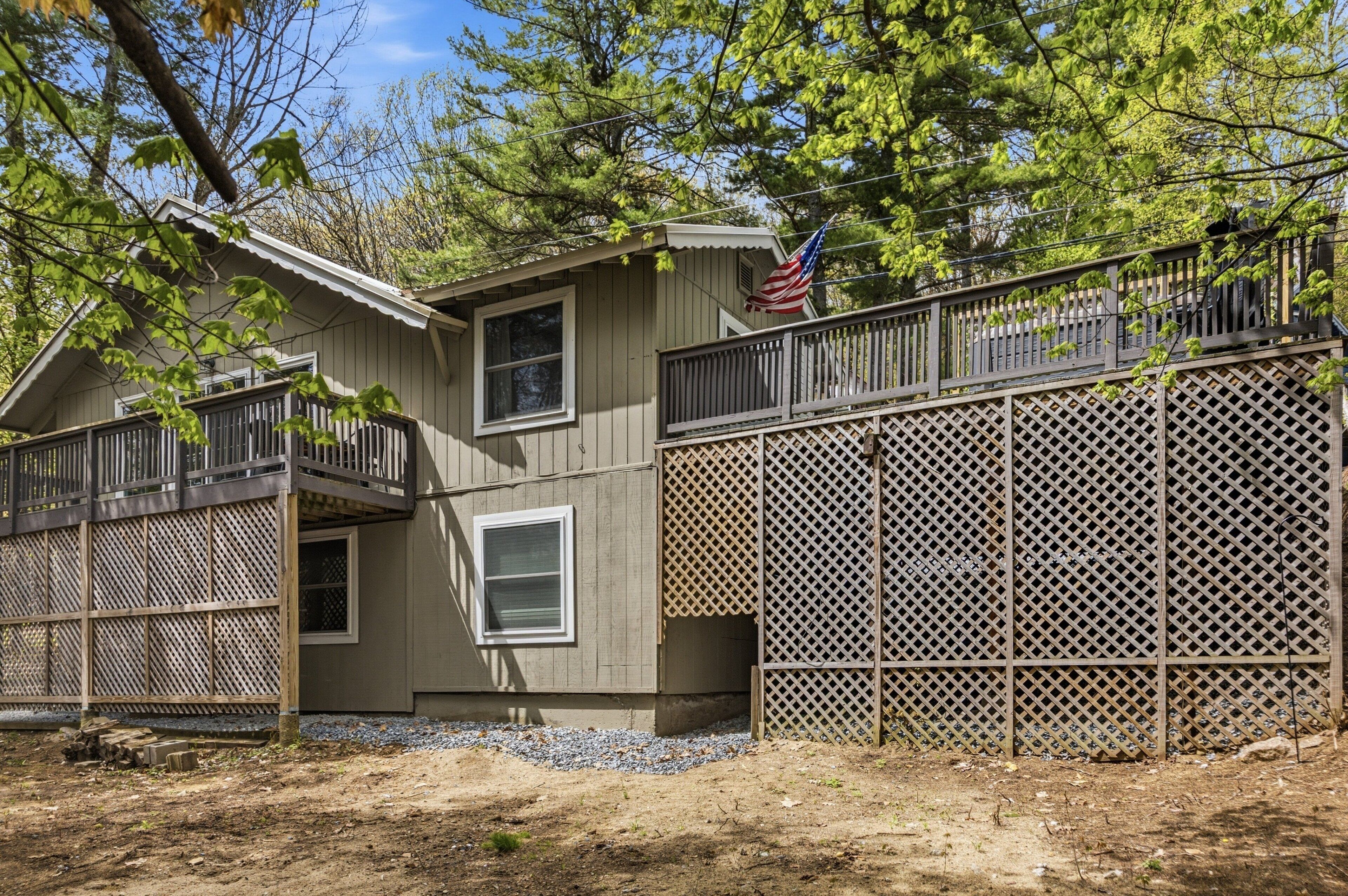 A two-story house with a balcony, a lattice fence, and an American flag.
