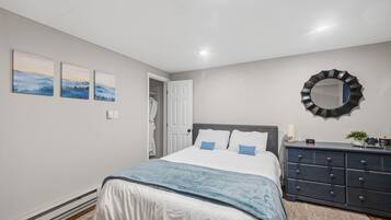 A bedroom with a bed, a dresser, a mirror, and three paintings on the wall.
