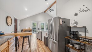 A modern kitchen with a stainless steel refrigerator, wooden countertops, and a dining area with a table and chairs. - Forest Chalet With Hot Tub Near Gunstock 3 Bedroom Home (Gilford)