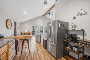 Cozinha moderna com geladeira de aço inoxidável, bancadas de madeira e um espaço de refeições com mesa e cadeiras.