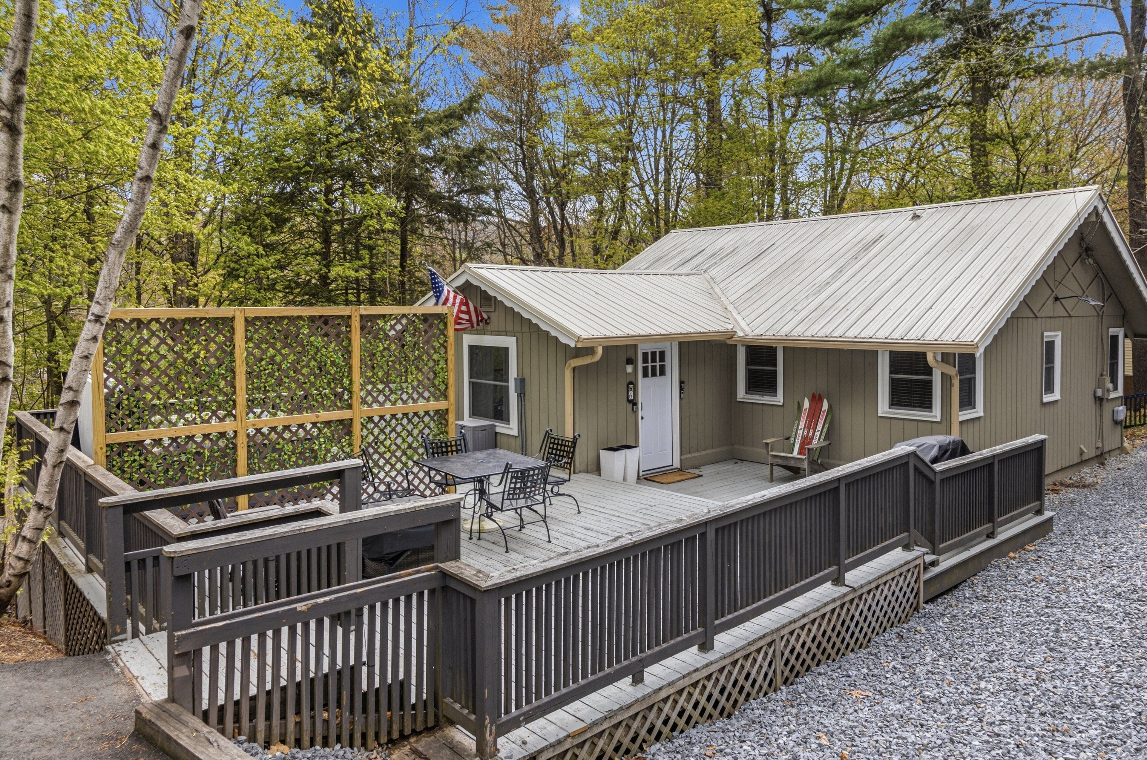 A cabin with a deck, a small porch, and a flag.