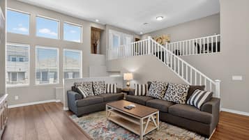 A living room with a sectional sofa, a coffee table, and a staircase.