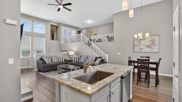 A spacious living area with a kitchen island, a dining table, and a staircase.