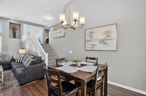 Ein Essbereich mit einer Chandelier, einem Gemälde und einer Treppe, die eine weitere Ebene hinaufführt.
