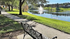 Ein Park mit Teich, Brunnen, Bank und einem Gehweg.