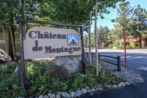 Schild für Château de Montagne mit Berg-Symbol, umgeben von Grünpflanzen und Felsen.