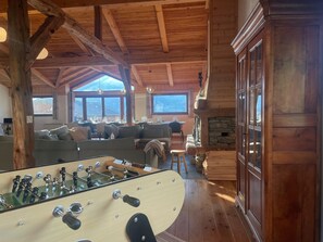 Ein Holzinterieur mit einem Kicker, Sofas und einem Steinkamin.
