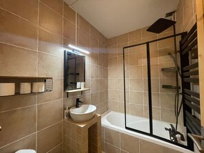Un ba ño moderno con bañera, lavabo, espejo y cabina de ducha.