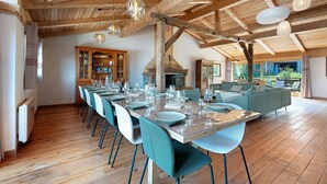 A spacious dining area with a long table set for a meal, wooden beams on the ceiling, and a view of the outdoors. - l'Hermine: Stunning Savoyard Chalet with Panoramic Views – Up to 15 Guests (La Plagne-Tarentaise)