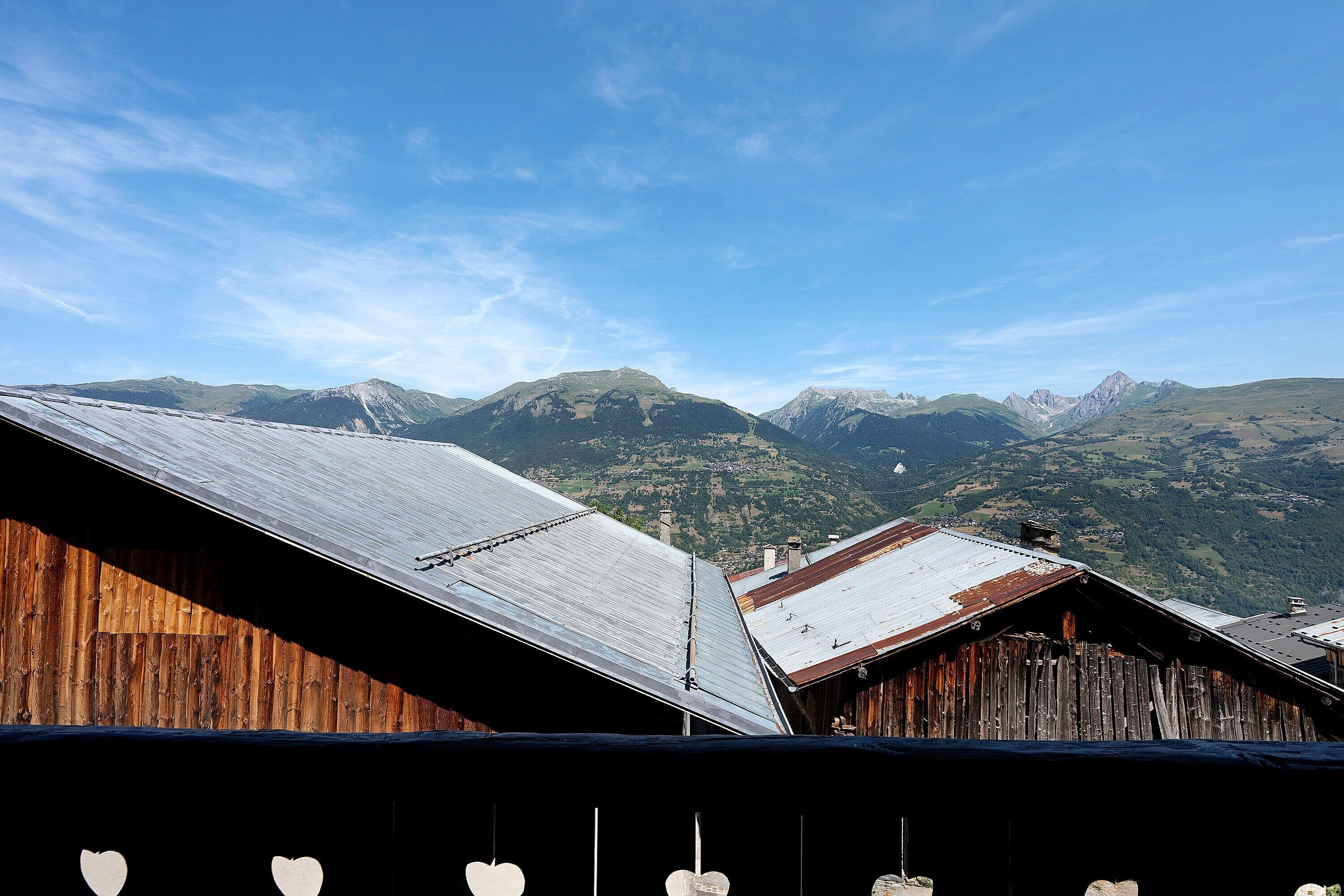 A mountain view with a wooden building and a metal roof.