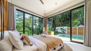 Une chambre avec un grand lit, un bureau et une vue sur une piscine.