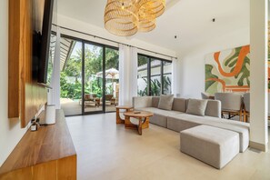 Ein modernes Wohnzimmer mit einem großen Ecksofa, einem Holztisch und einem flachbildfernseher an der Wand.