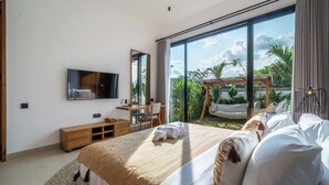 Une chambre d’hôtel moderne dotée d’un grand lit, d’une télévision, d’un bureau et d’un balcon offrant une vue sur la verdure.