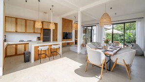 Une cuisine moderne dotée d’un îlot central, de meubles en bois et de luminaires suspendus.