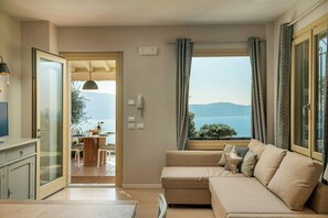 Ein modernes Wohnzimmer mit Sofa, Essbereich mit Tisch und Stühlen sowie Meerblick.