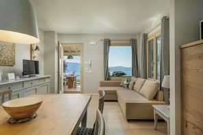 Ein modernes Wohnzimmer mit Sofa, Esstisch und Blick ins Freie.
