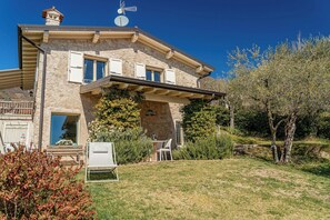 Ein Steinhaus mit Balkon, Satellitenschüssel und Windmühle auf dem Dach.