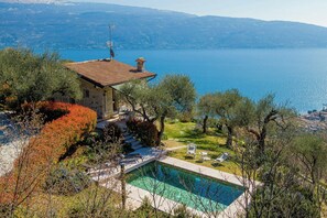 Ein Haus mit Swimmingpool, umgeben von Bäumen und Blick auf einen See.