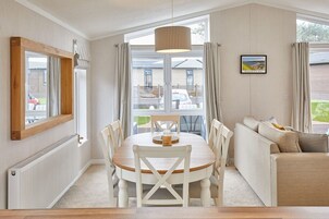 A dining area with a table, chairs, and a hanging light fixture.