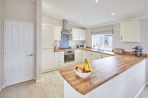 Una cocina moderna con armarios blancos, encimera de madera, horno empotrado y microondas.