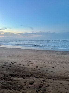 Une plage où l’on peut voir des empreintes de pas et où le ciel est dégagé.