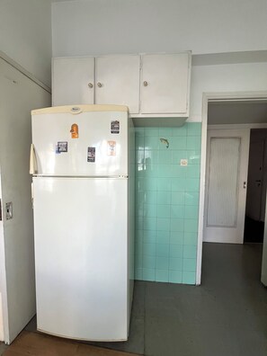 Eine Küche mit einem weißen Kühlschrank, einer türkis gefliesten Spritzschutzwand und weißen Schränken.
