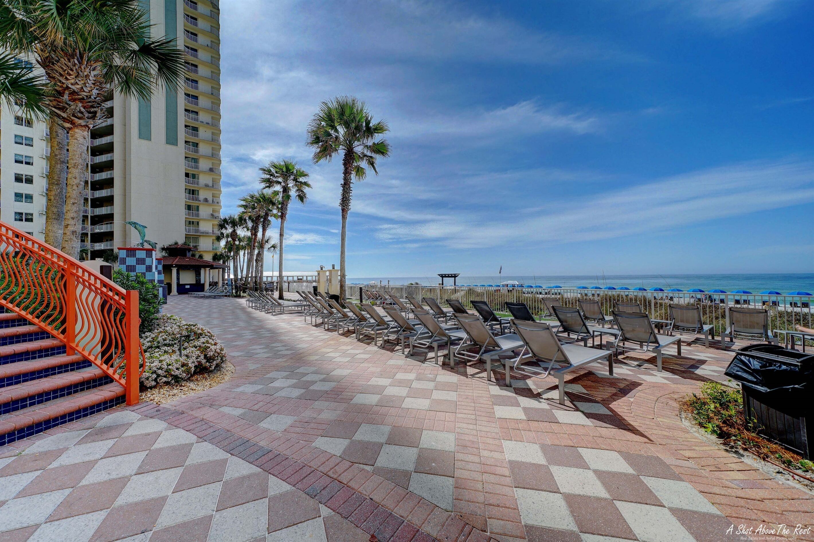 A beachfront patio with lounge chairs and a staircase leading to an upper level.