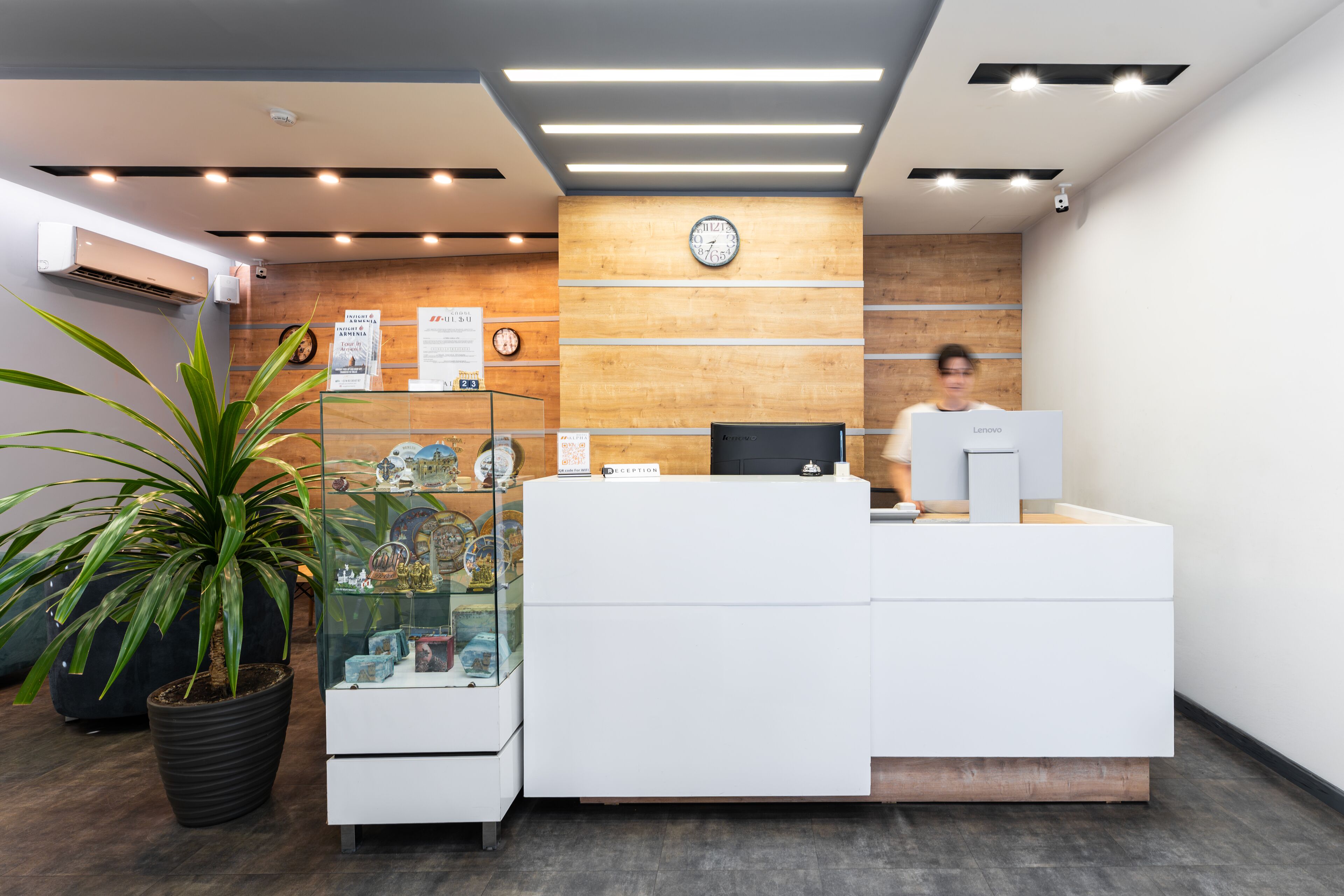 Un comptoir d’accueil avec une horloge, une plante en pot et une vitrine.