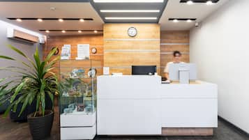 Un comptoir d’accueil avec une horloge, une plante en pot et une vitrine.