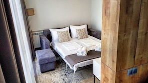 Un dormitorio con cama, dos almohadas, una mesita de noche, una lámpara y un armario de madera.