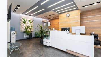 Un espace d’accueil comprenant un comptoir de réception en bois, une horloge et un distributeur d’eau.